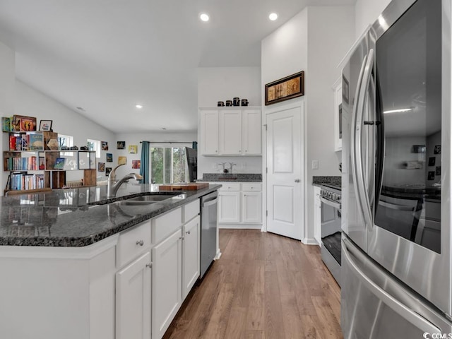 kitchen with stainless steel appliances, wood-type flooring, dark stone countertops, white cabinets, and sink