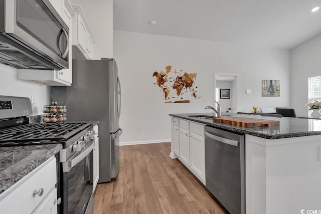 kitchen featuring white cabinets, light hardwood / wood-style flooring, stainless steel appliances, sink, and an island with sink