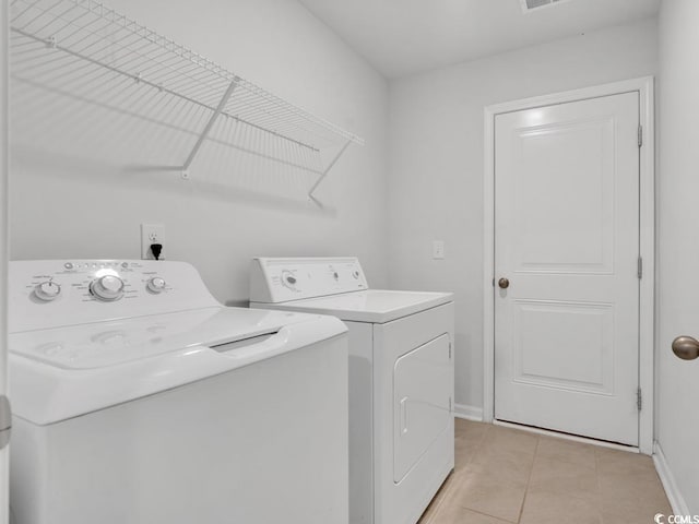 laundry room featuring washer and clothes dryer and light tile floors