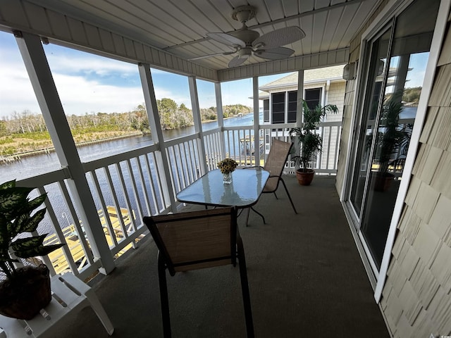 sunroom / solarium with ceiling fan and a water view