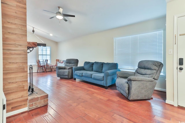 living room with hardwood / wood-style flooring, wooden walls, ceiling fan, and vaulted ceiling