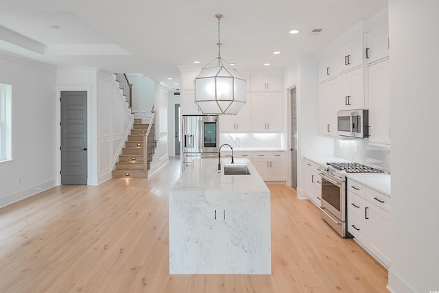 kitchen featuring white cabinets, light hardwood / wood-style floors, appliances with stainless steel finishes, and sink