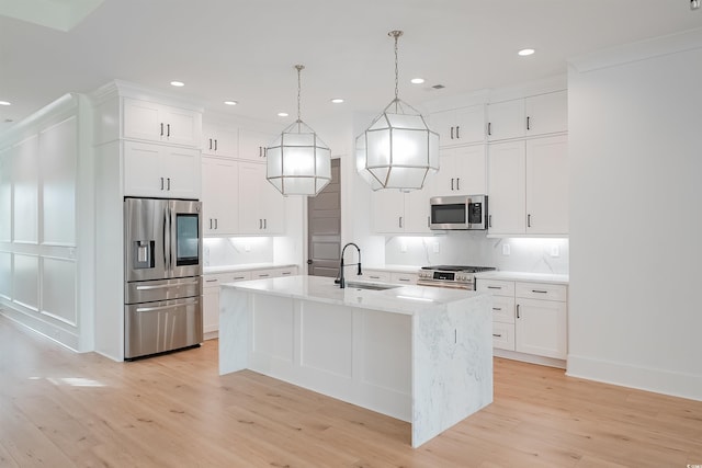 kitchen with light hardwood / wood-style floors, backsplash, stainless steel appliances, an island with sink, and pendant lighting