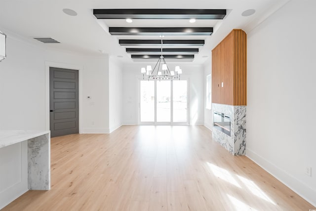 unfurnished living room featuring beamed ceiling, light hardwood / wood-style flooring, and an inviting chandelier