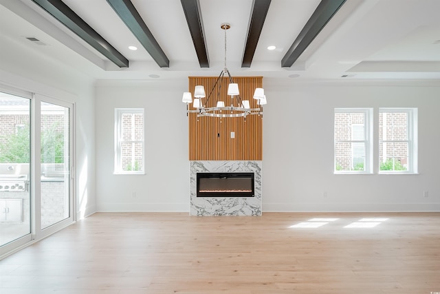 unfurnished living room with beamed ceiling, an inviting chandelier, light wood-type flooring, and a premium fireplace