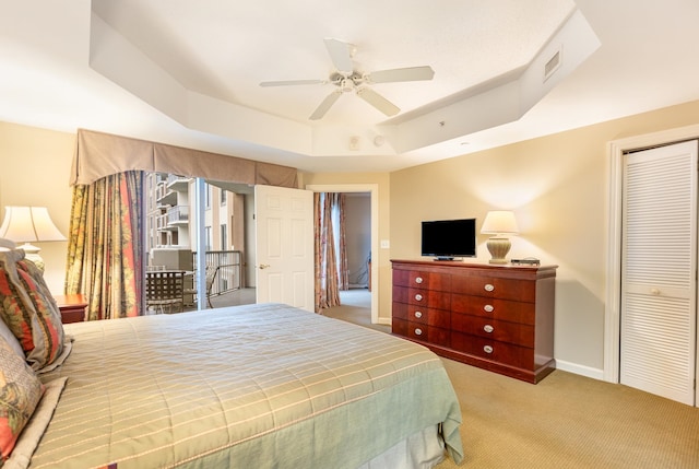 carpeted bedroom featuring ceiling fan, a raised ceiling, and a closet