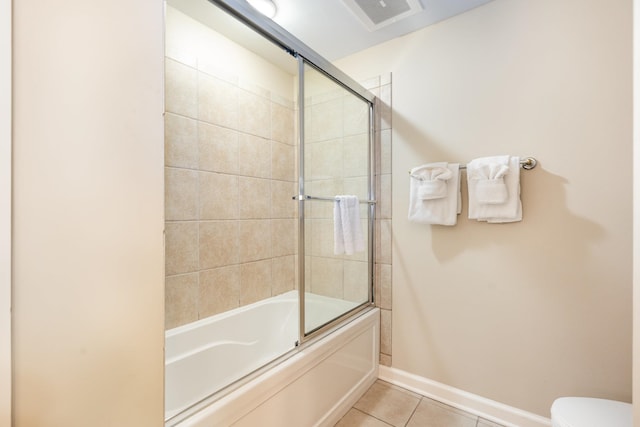 bathroom with tile patterned floors, toilet, and shower / bath combination with glass door