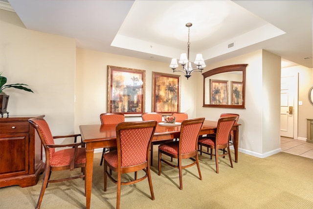 carpeted dining room featuring a chandelier and a tray ceiling