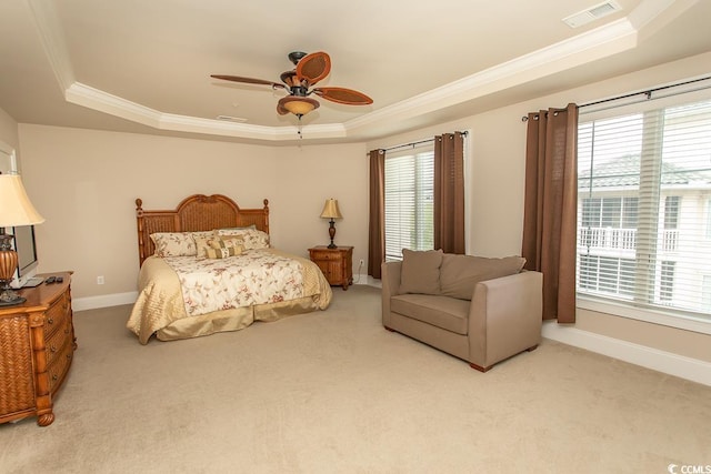 carpeted bedroom featuring ceiling fan, a raised ceiling, ornamental molding, and multiple windows