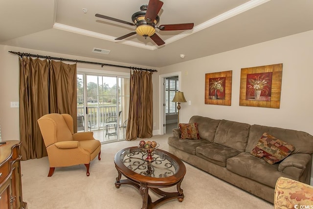 carpeted living room with a raised ceiling, ornamental molding, and ceiling fan