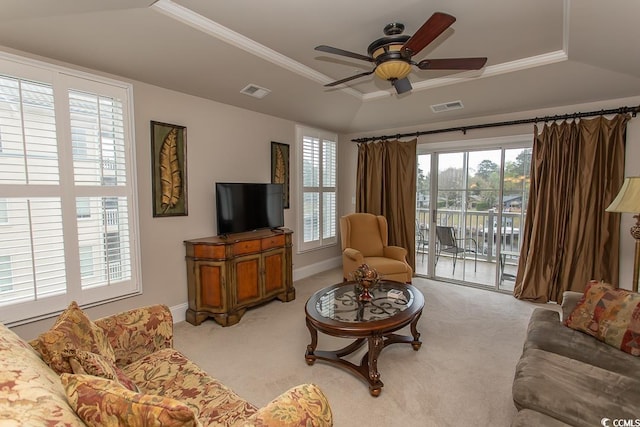 living room with ceiling fan, ornamental molding, light colored carpet, and a raised ceiling