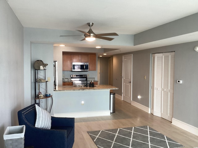 kitchen with kitchen peninsula, light hardwood / wood-style flooring, ceiling fan, and stainless steel appliances