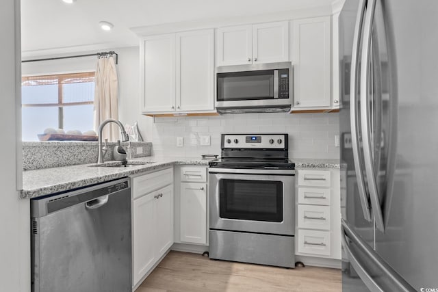 kitchen featuring white cabinets, sink, appliances with stainless steel finishes, and light hardwood / wood-style flooring