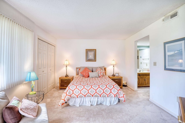 carpeted bedroom featuring ensuite bathroom, a closet, and a textured ceiling