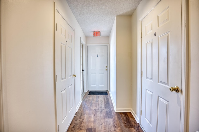 hallway with a textured ceiling and dark hardwood / wood-style floors