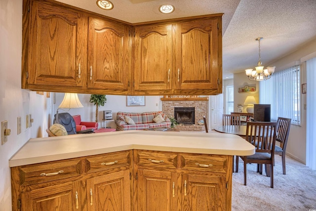 kitchen with a brick fireplace, a textured ceiling, decorative light fixtures, light colored carpet, and a chandelier