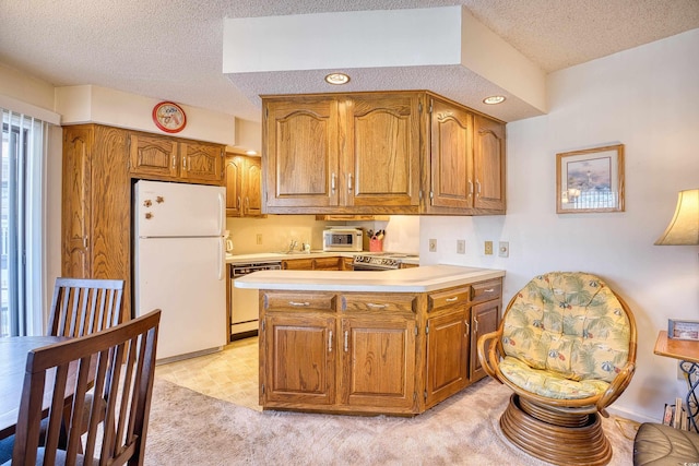 kitchen with a textured ceiling, kitchen peninsula, and white appliances