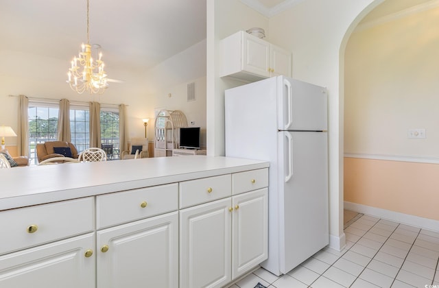 kitchen featuring hanging light fixtures, white cabinetry, white fridge, light tile flooring, and an inviting chandelier