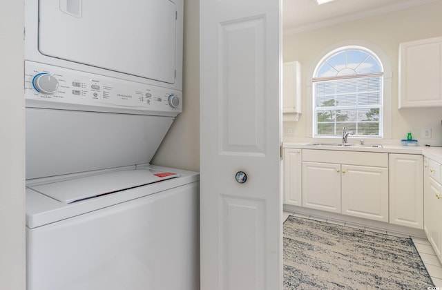 clothes washing area with crown molding, sink, stacked washer and clothes dryer, and light tile flooring