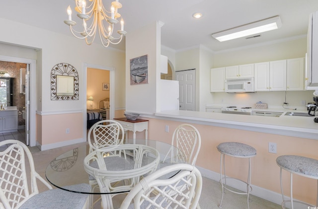 kitchen featuring white appliances, light colored carpet, a chandelier, decorative light fixtures, and white cabinetry