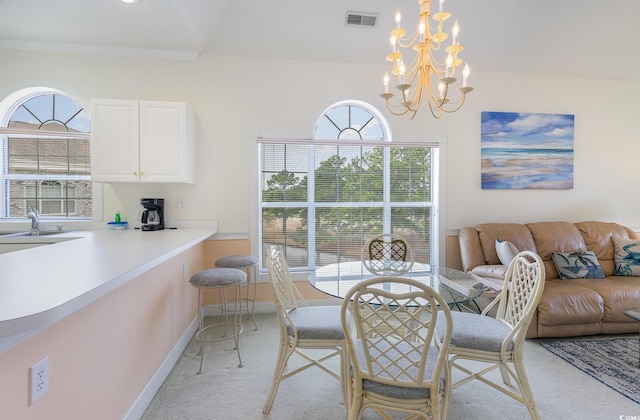 dining area featuring sink, a notable chandelier, and light colored carpet