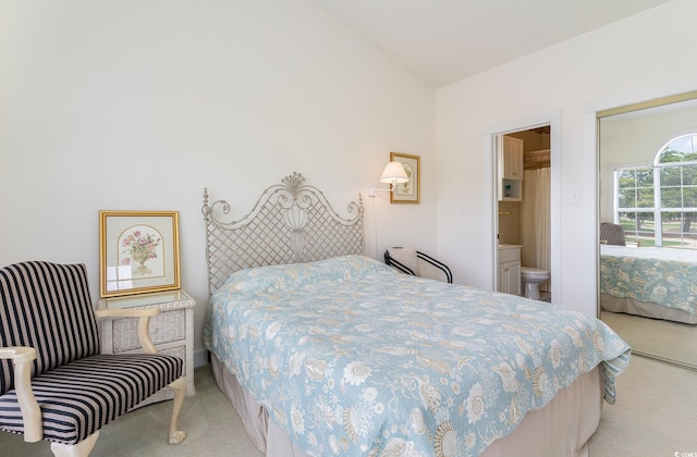 bedroom featuring connected bathroom, light colored carpet, and vaulted ceiling