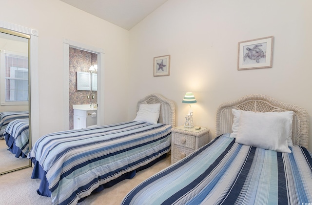 bedroom featuring lofted ceiling, connected bathroom, and light carpet