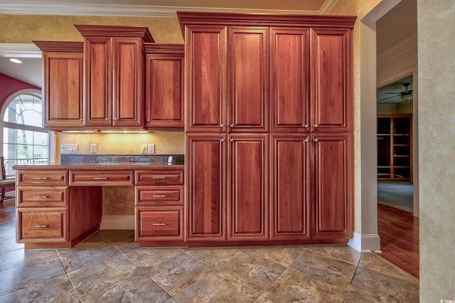 kitchen with ceiling fan, built in desk, ornamental molding, and tile floors