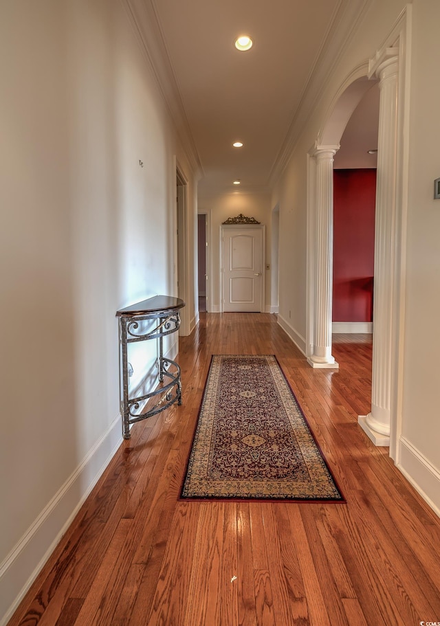 hall with dark hardwood / wood-style flooring, decorative columns, and ornamental molding