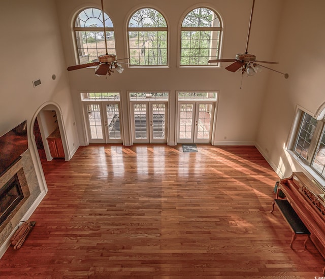 unfurnished living room with french doors, ceiling fan, a towering ceiling, and dark hardwood / wood-style flooring