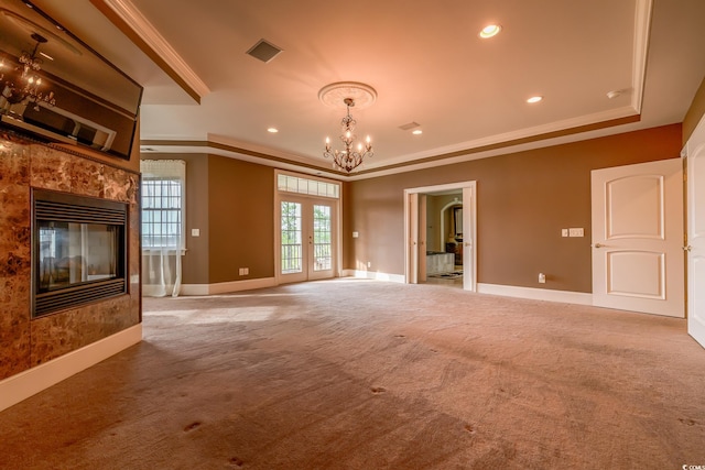 unfurnished living room with light carpet, crown molding, a fireplace, and a chandelier