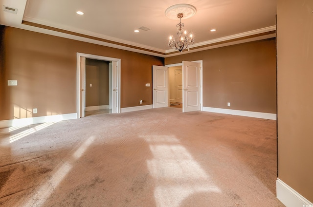 carpeted empty room featuring a notable chandelier, crown molding, and a tray ceiling