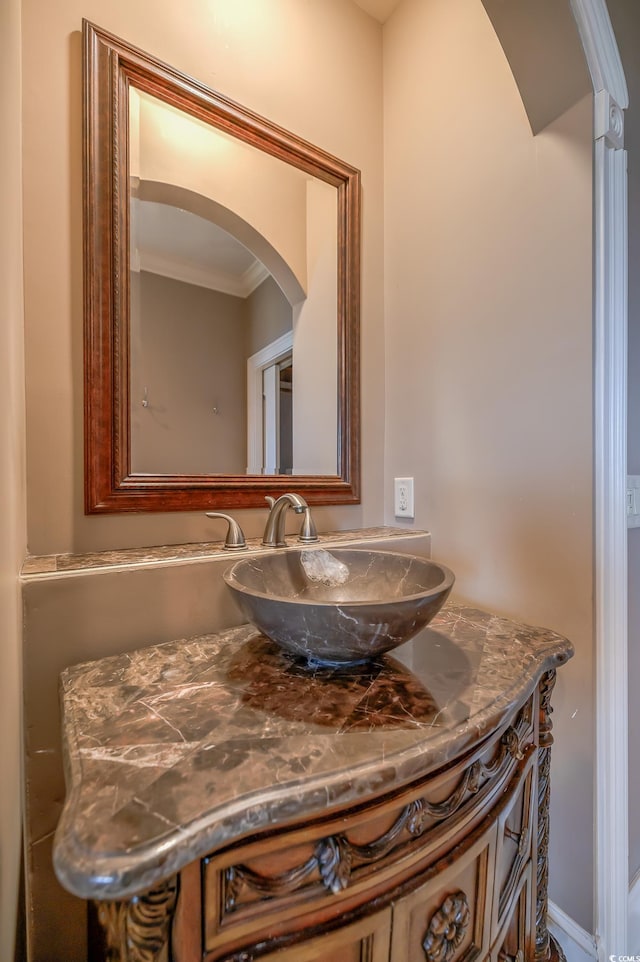 bathroom with ornamental molding and vanity with extensive cabinet space