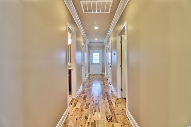 hallway with ornamental molding and light hardwood / wood-style flooring