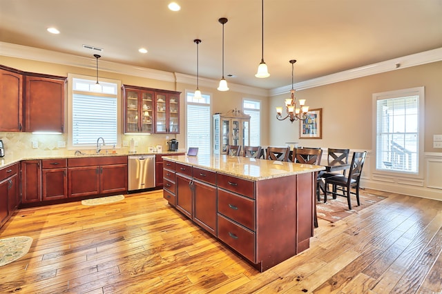 kitchen featuring backsplash, light hardwood / wood-style floors, decorative light fixtures, and stainless steel dishwasher