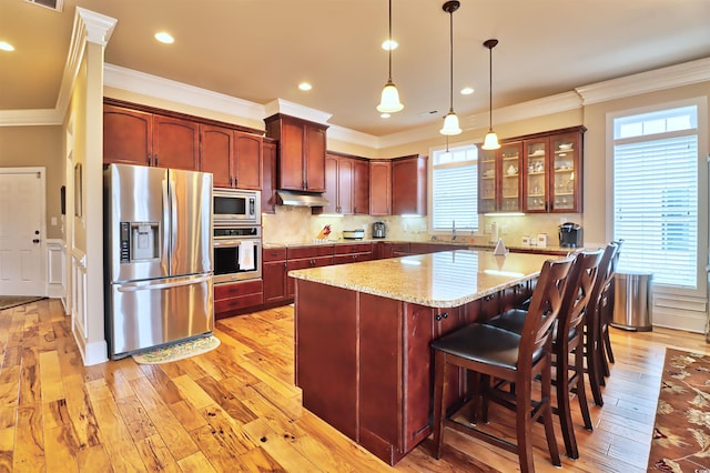 kitchen with hanging light fixtures, light hardwood / wood-style floors, tasteful backsplash, and stainless steel appliances