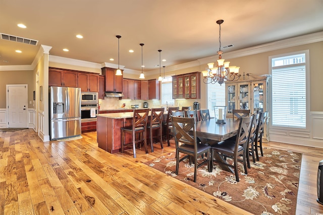 dining room featuring a healthy amount of sunlight, light wood-type flooring, crown molding, and an inviting chandelier