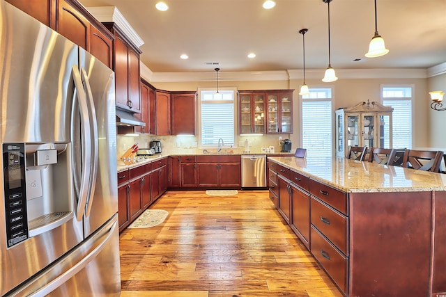 kitchen featuring pendant lighting, light wood-type flooring, stainless steel appliances, sink, and tasteful backsplash