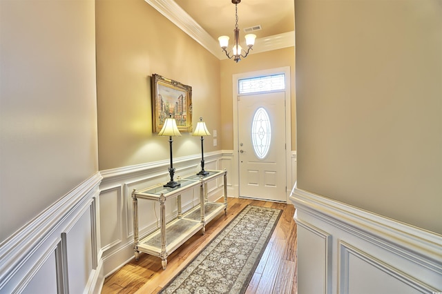 entrance foyer featuring ornamental molding, wood-type flooring, and a notable chandelier