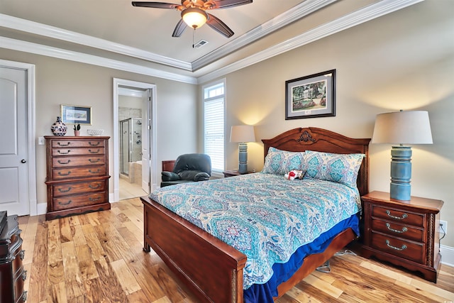 bedroom featuring ensuite bath, light hardwood / wood-style flooring, a tray ceiling, ornamental molding, and ceiling fan