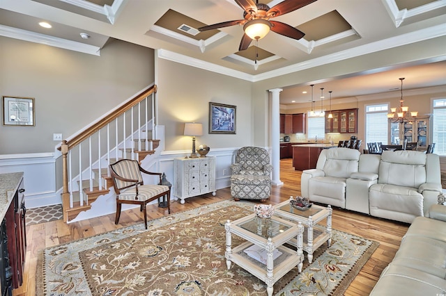 living room with ceiling fan with notable chandelier, hardwood / wood-style floors, coffered ceiling, and ornamental molding