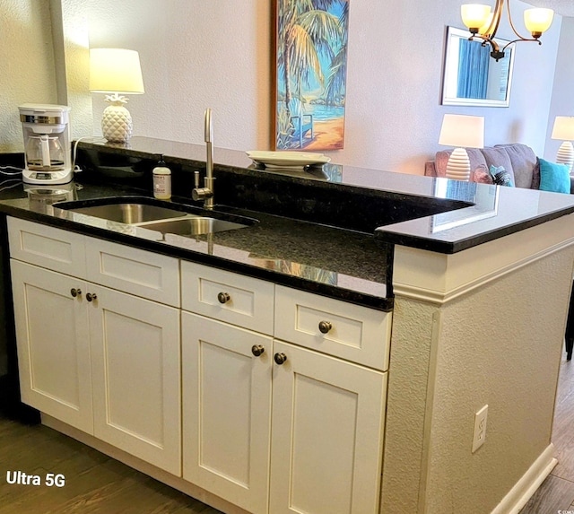 kitchen with dark hardwood / wood-style floors, white cabinetry, hanging light fixtures, and sink