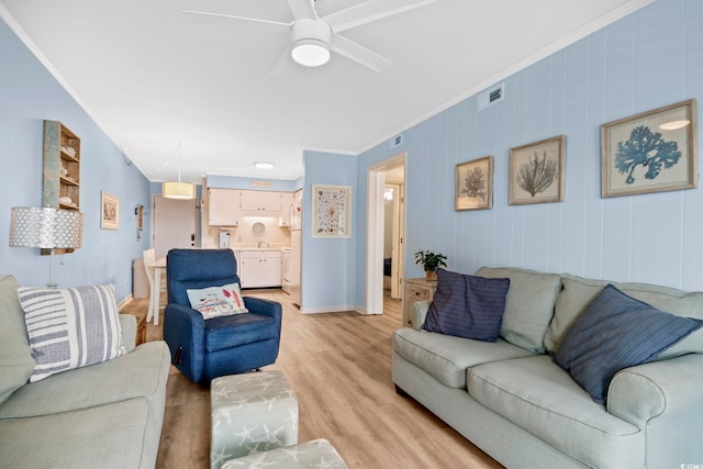 living room with light hardwood / wood-style flooring, ceiling fan, sink, and crown molding