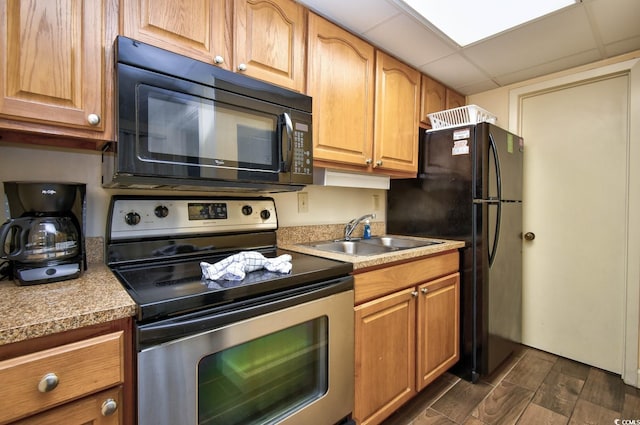 kitchen with sink, a drop ceiling, dark wood-type flooring, and black appliances