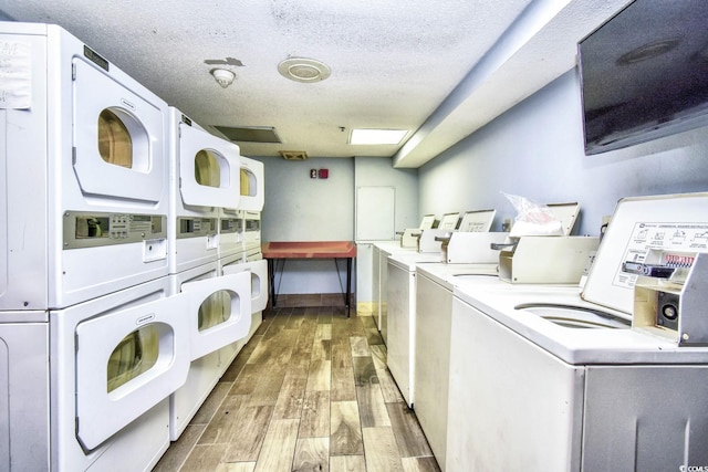 washroom featuring washing machine and clothes dryer, a textured ceiling, stacked washing maching and dryer, and wood-type flooring