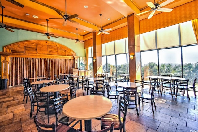 tiled dining space with ceiling fan and a towering ceiling