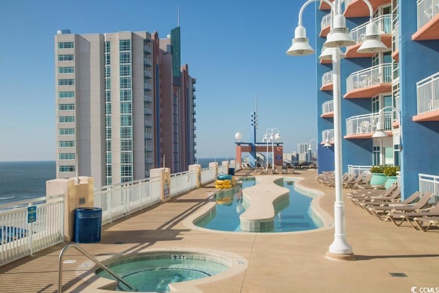 view of pool featuring a hot tub and a water view