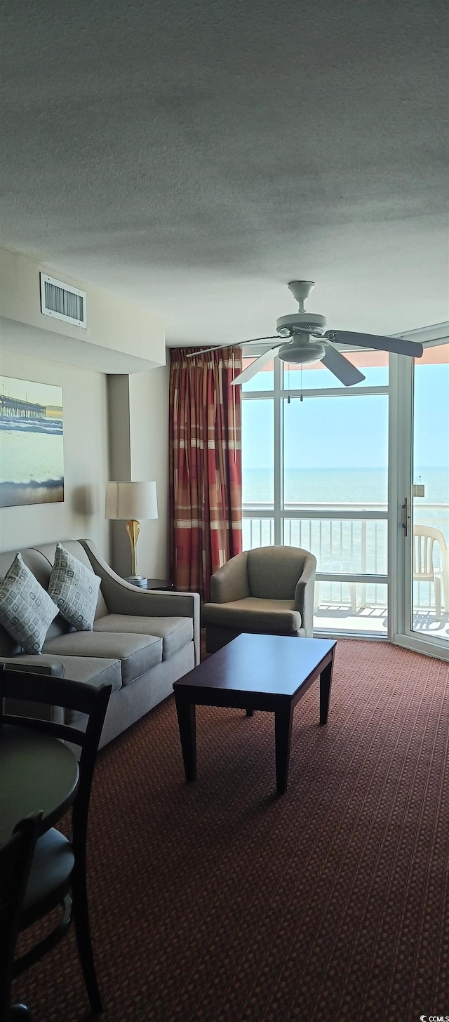 carpeted living room with ceiling fan and a textured ceiling