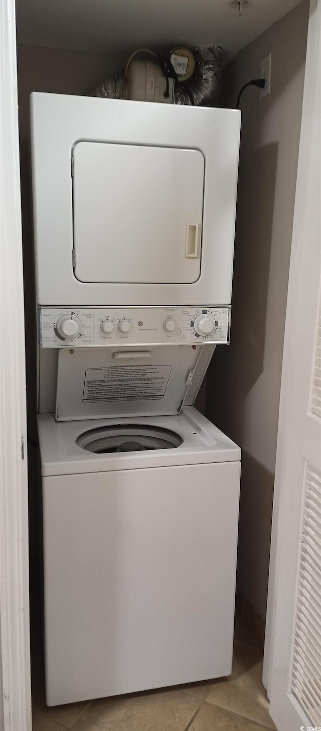 laundry area with light tile floors and stacked washer / drying machine