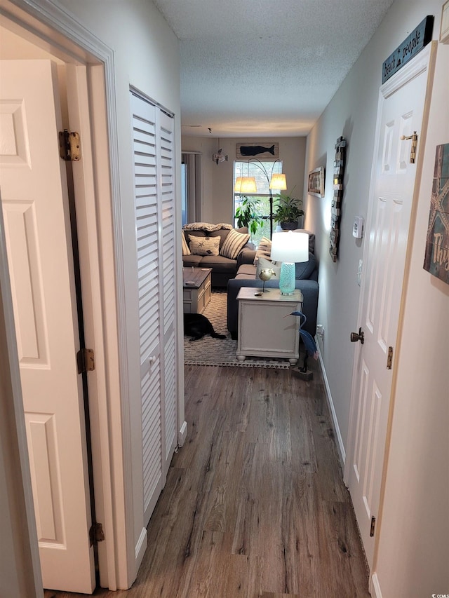 corridor featuring dark hardwood / wood-style flooring and a textured ceiling